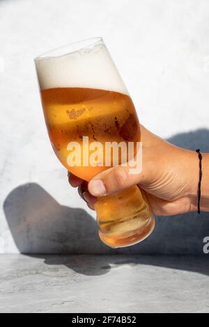 Main tenant un verre avec de la bière IPA sur un journée chaude Banque D'Images