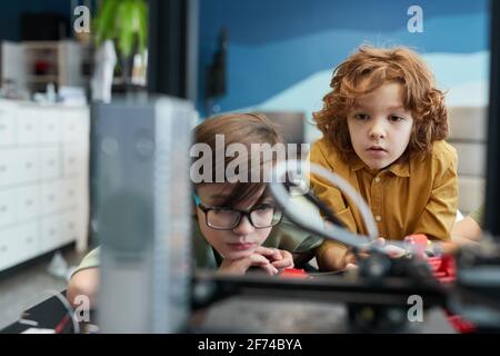 Portrait de deux écoliers regardant une imprimante 3D pendant un cours d'ingénierie à l'école moderne, espace de copie Banque D'Images