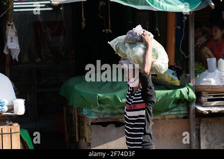 Un homme transportant une lourde charge de légumes dans une zone de marché, Cebu City, Philippines Banque D'Images