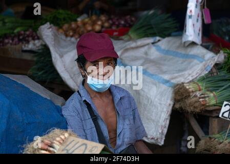 Un vendeur de légumes dans un marché regarde la caméra, Cebu City, Philippines Banque D'Images