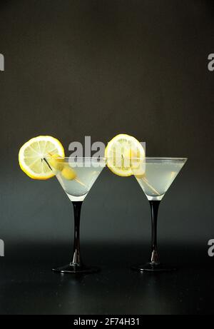 Deux verres de martini avec vermouth blanc, tranches de citron et olives sur fond noir. Gros plan. Banque D'Images