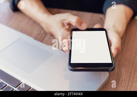 Vue de dessus mains femelles tenant un smartphone avec écran blanc vierge. Femmes mains espace de travail, main gros-up tenant smartphone écran vide pour le texte et c Banque D'Images