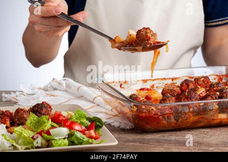 Recette traditionnelle turque, boulettes de viande en sauce tomate, pommes de terre et rondelles d'oignon cuites au four. Le repas appelé kofteli patates est servi avec la salade A. Banque D'Images