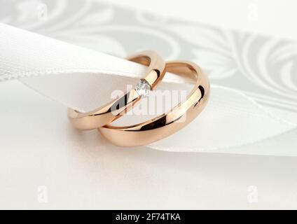 Deux anneaux de mariage dorés avec diamant sur fond gris Banque D'Images