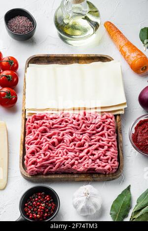 Le concept de la cuisine de lasagnes. Ingrédients, feuilles de lasagne, basilic, tomates cerises, parmesan, ail, ensemble de poivre, sur fond de pierre blanche Banque D'Images