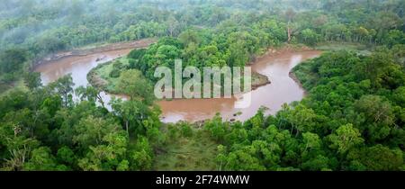 Une vue aérienne d'un virage à l'arc-en-ciel dans la rivière Mara et sa forêt environnante lors d'une matinée brumeuse dans la réserve de Masai Mara, au Kenya. Banque D'Images