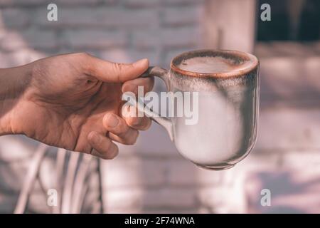 Mains d'un homme ou d'un barista tenant une tasse de chaud latte à café avec art en mousse en forme de coeur Banque D'Images