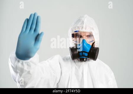 un homme en costume présentant un risque biologique fait un panneau d'arrêt. Banque D'Images