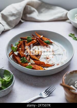 Grand angle de délicieuses frites de patate douce à la crème aigre et herbes servies sur table Banque D'Images