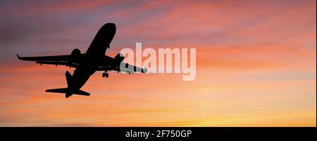 Silhouette d'un avion atterrissant à l'aéroport contre le arrière-plan du coucher du soleil Banque D'Images