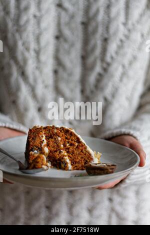 Préparer une plaque de maintien anonyme avec une tranche de gâteau à la carotte savoureuse avec fromage à la crème et biscuit humide Banque D'Images