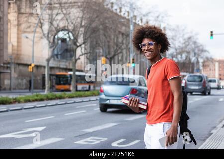 Jolie femme afro-américaine avec cheveux bouclés et décontracté tenue sur fond rose et souriante Banque D'Images