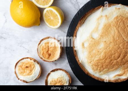 Vue de dessus de la tarte appétissante à la meringue servie sur une table en marbre avec des citrons frais dans la cuisine Banque D'Images