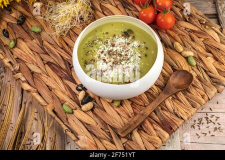 Vue de dessus de l'appétissant soupe à la crème végétalienne avec pistaches écrasées sur le dessus du tapis en osier avec une cuillère en bois Banque D'Images