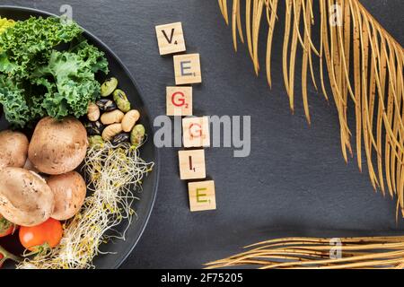 Vue en hauteur du titre décoratif près de l'assiette avec pommes de terre cuites et les feuilles de chou kale sur les noix et les pousses sur le gris arrière-plan Banque D'Images