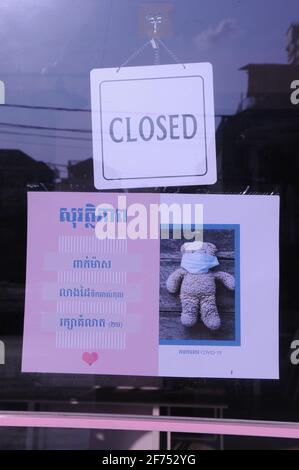 En raison d'une récente épidémie de COVID - 19, un magasin fermé de jouets pour enfants met en place un signe mignon dans le script khmer d'avertissement sur les dangers du virus pendant la pandémie du coronavirus. Phnom Penh, Cambodge. © Kraig Lieb Banque D'Images