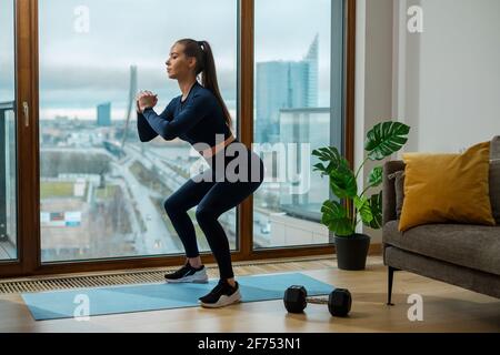 Brunette femme avec queue de cheval brune en position de squat dans le Lodge Banque D'Images