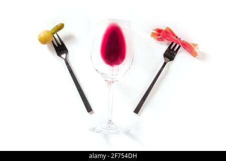 En-cas au vin. Un verre de vin avec une olive et une tranche de jamon sur les fourchettes Banque D'Images
