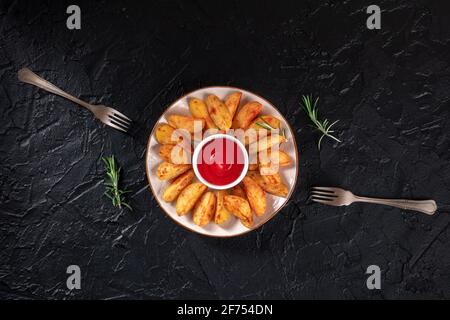 Quartiers de pommes de terre cuits au romarin et deux fourchettes, grenaille à plat au-dessus Banque D'Images