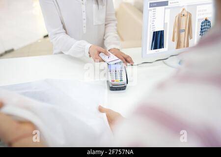 Main de femme tenant le smartphone au-dessus du terminal de pos Banque D'Images