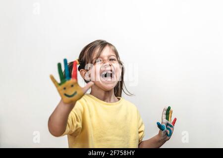 Bonne petite fille sans dents avec les mains peintes riant et ayant Amusement - petite fille qui peint ses mains avec Smiley visages et nombres - Childho Banque D'Images