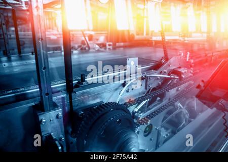 Ligne de convoyeur vide avec mécanisme de chaîne comme arrière-plan industriel bleu abstrait avec des évasements jaunes et rouges. Banque D'Images