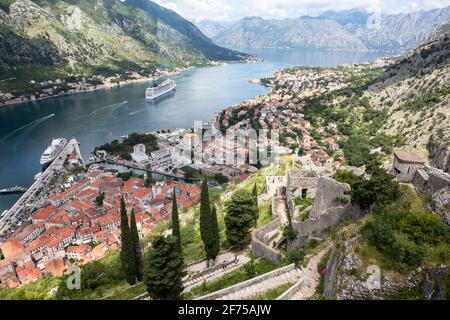 Vue panoramique sur le golfe de Kotor (Boka Kotorska) avec la ville médiévale, le port maritime avec les bateaux à ferryboat et les montagnes environnantes. Vue depuis les murs du fort. Banque D'Images