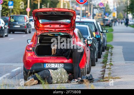 Riga, Lettonie - 30 septembre 2020 : homme et femme réparant une voiture garée sur le bord de la route Banque D'Images