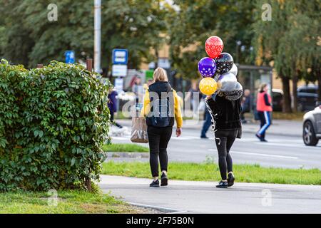 Riga, Lettonie - 30 septembre 2020 : adolescent marchant dans la rue avec des ballons colorés à portée de main Banque D'Images