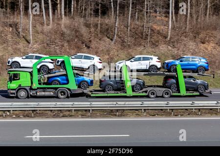 Camion-porteur Adampol Scania chargé de nouvelles voitures Kia Sportage sur l'autoroute. Banque D'Images