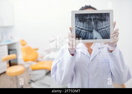 Dentiste tenant une tablette numérique avec dents x-ray à l'écran et recherche de toute inflammation Banque D'Images