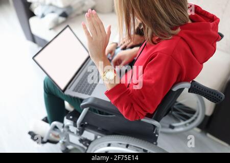 Femme handicapée en fauteuil roulant, agitant la main à l'écran de l'ordinateur portable Banque D'Images