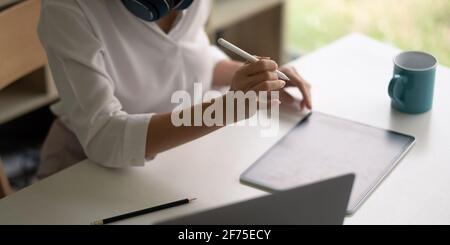 Gros plan femme d'affaires main à l'aide d'un stylet, travailler sur une tablette numérique sur le lieu de travail. Banque D'Images