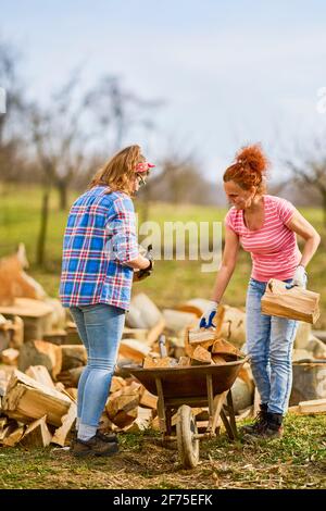 deux femmes travaillent ensemble pour mettre du bois de chauffage pour l'hiver Banque D'Images