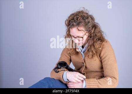 Détail d'une belle femme avec des lunettes et des cheveux bruns, assis souriant avec un chiot Jack Russel Terrier dans ses bras Banque D'Images