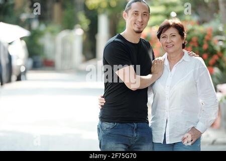 Portrait d'une jeune femme de race mixte, assez mûre et gaie, et de son adulte fils debout à l'extérieur Banque D'Images