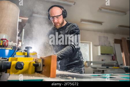 Menuisier travaillant sur les machines à scier le travail du bois dans l'atelier de menuiserie, concept industriel Banque D'Images