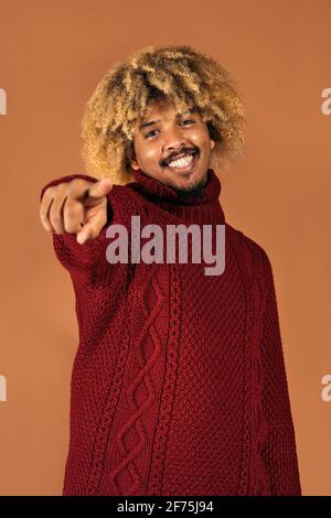 Photo de smiley afro homme souriant et regardant l'appareil photo en studio tourné sur fond marron. Banque D'Images