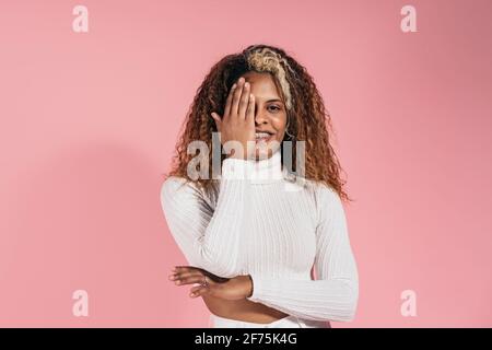 Photo de la femme smiley avec des cheveux bouclés regardant l'appareil photo pendant la prise de vue en studio. Banque D'Images