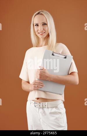 Portrait d'une jeune femme d'affaires souriante et attrayante avec un presse-papiers entre les mains regarder l'appareil photo Banque D'Images