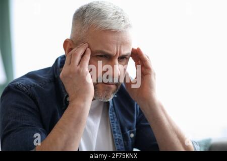 Gros plan de l'homme mature à cheveux gris souffrant de migraine Banque D'Images