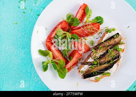 Sandwich - Smorrebrod avec des sparats et de la salade de tomates sur l'assiette blanche. Cuisine danoise. Concept écologique. Vue de dessus, plan d'appartement Banque D'Images