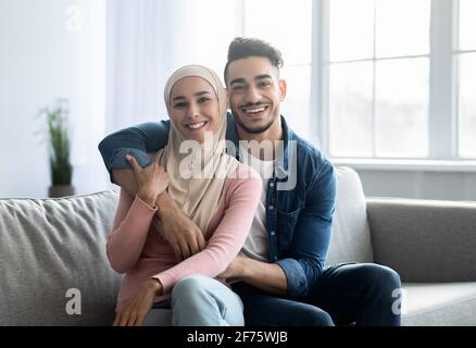 Couple arabe aimant assis sur un canapé à la maison, embrassant Banque D'Images