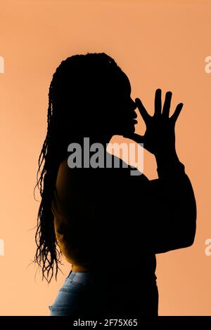 Photo de la femme noire non reconnue avec ses mains ensemble sur fond marron. Banque D'Images