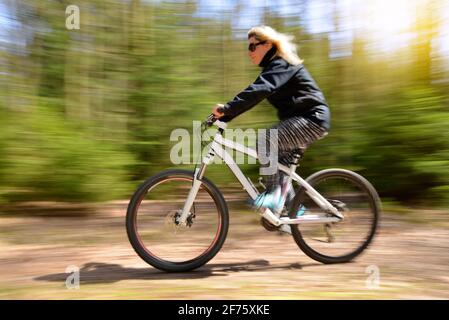 Femme à vélo de montagne sur un sentier forestier. Concept de sport et de vie active. Prise de vue floue en mouvement. Banque D'Images