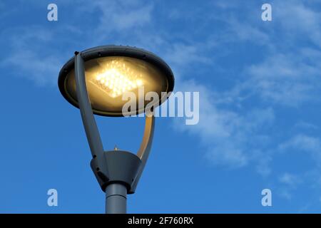 Lampe LED sur fond bleu ciel et blanc nuages. Éclairage électrique, lanterne de rue à économie d'énergie Banque D'Images