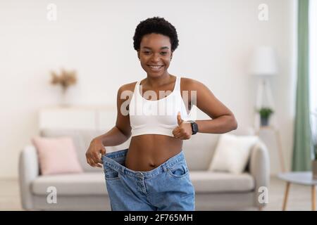 Gaie Black femme portant des jeans énormes après avoir fait un petit plus à la maison Banque D'Images