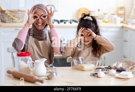 Une maman musulmane joyeuse et sa petite fille se berce ensemble cuisine Banque D'Images