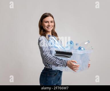 Concept de tri des déchets. Conteneur de transport de jeunes femmes Smiling avec bouteilles en plastique vides Banque D'Images