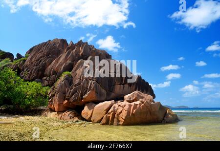 Île de la Digue, océan Indien, Seychelles. Grande roche de granit sur la plage de l'Anse grosse Roche. Paysage tropical avec mer et ciel bleu. Banque D'Images